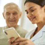 Smiling nurse and senior citizen looking at smartphone screen